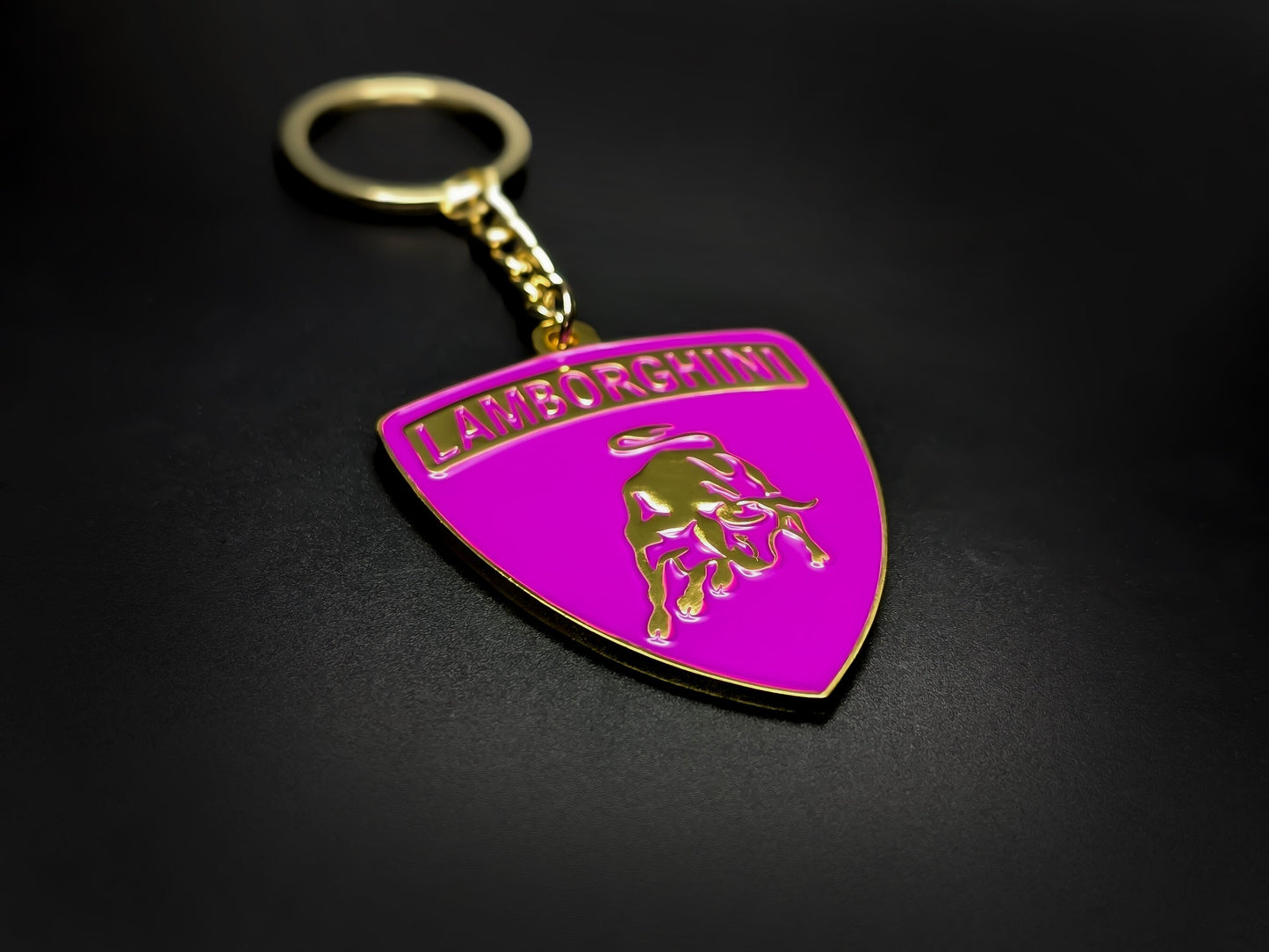 High-gloss purple Lamborghini badge keychain on a dark background, showcasing the polished gold-tone metal and chain.