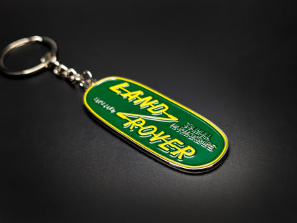 High-gloss Land Rover heritage badge keychain on a dark background, showing the polished silver edges and sturdy chain.