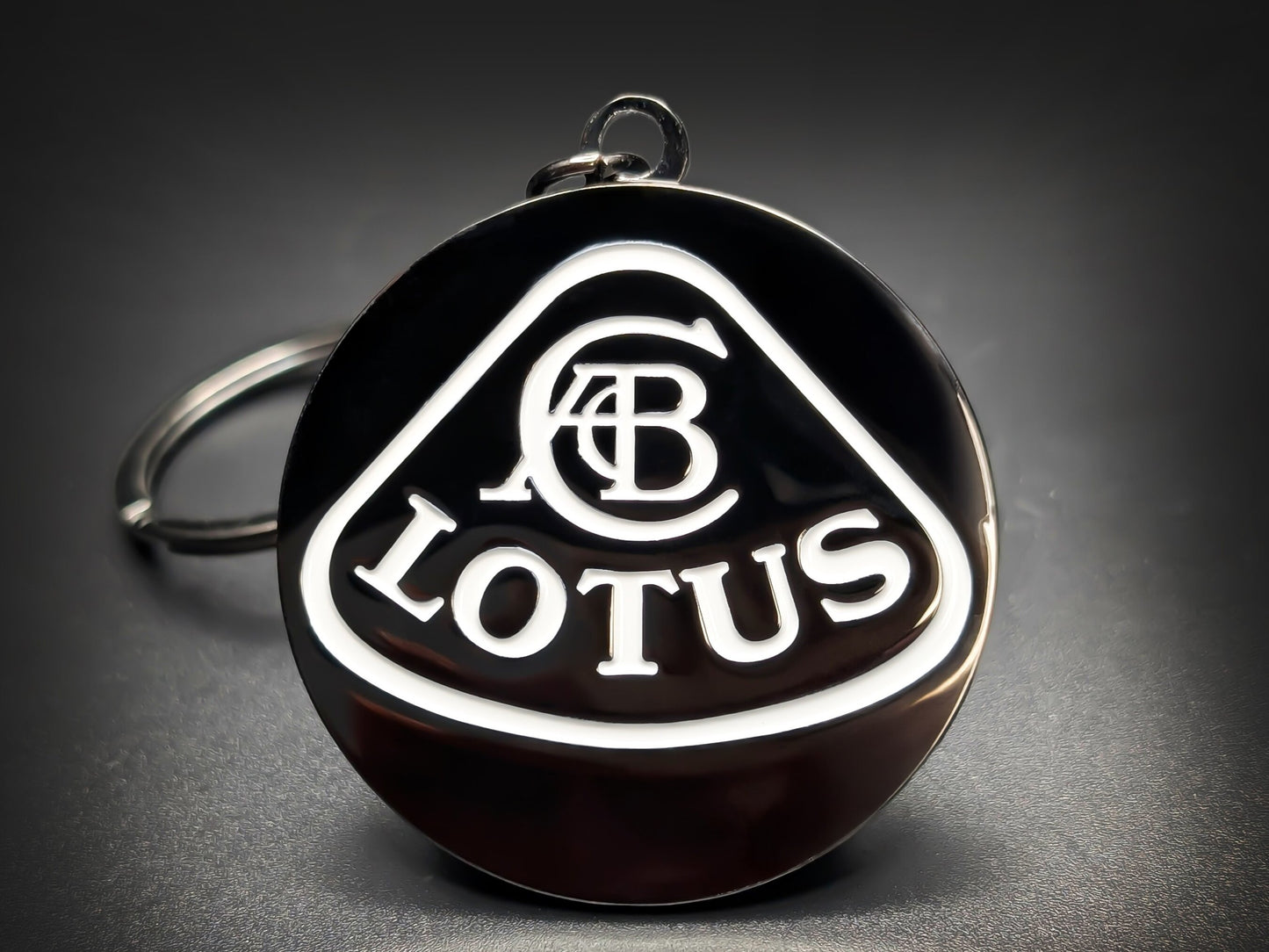 Lotus car badge keychain in minimalist black and white enamel, featuring the ACBC crest and Lotus wordmark.