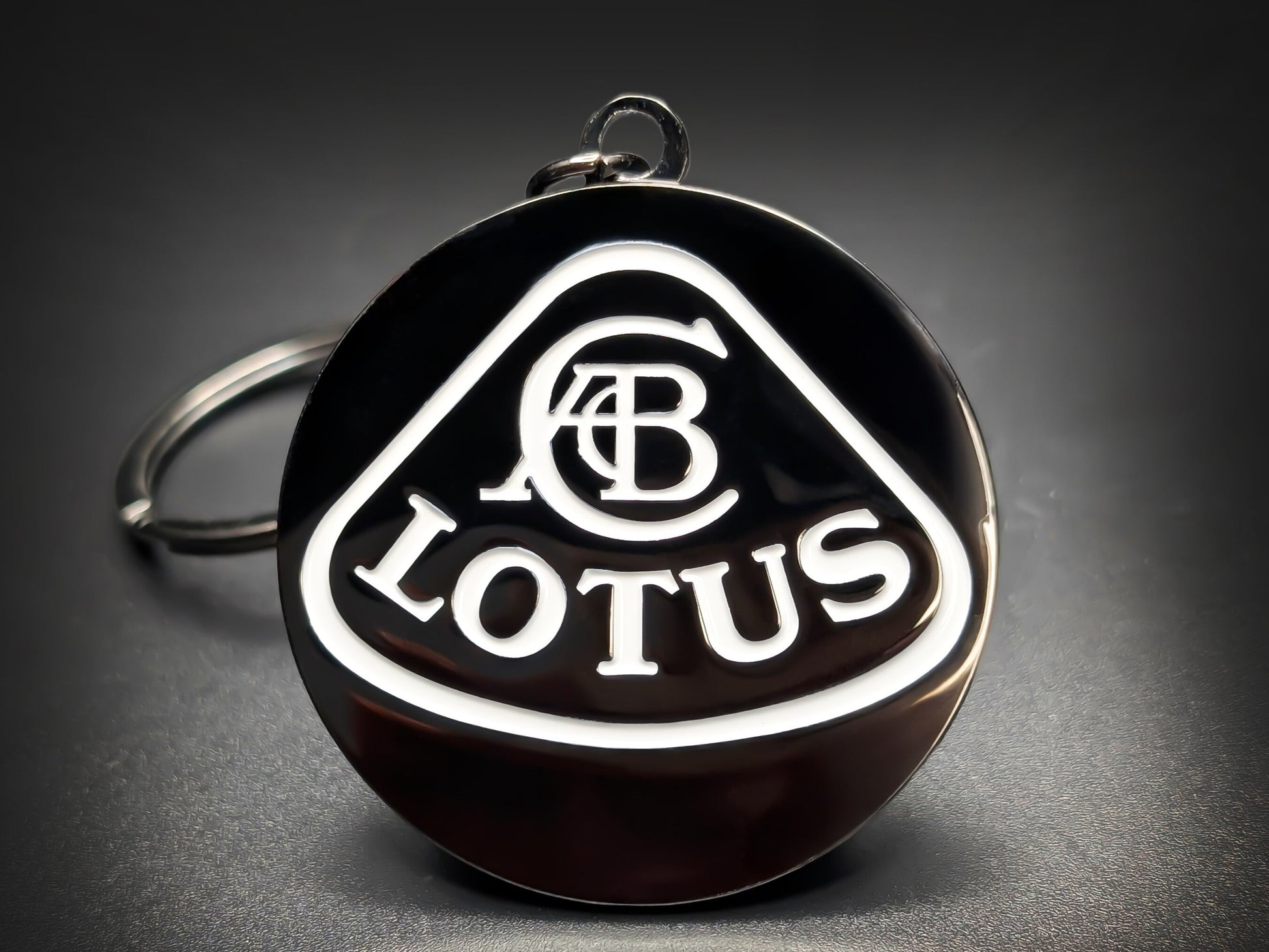 Lotus car badge keychain in minimalist black and white enamel, featuring the ACBC crest and Lotus wordmark.