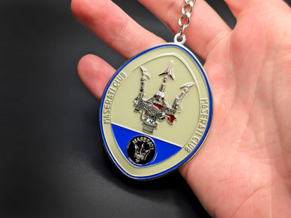 Hand holding the Maserati Club oval badge keychain to demonstrate its size and heavy-duty metal construction.