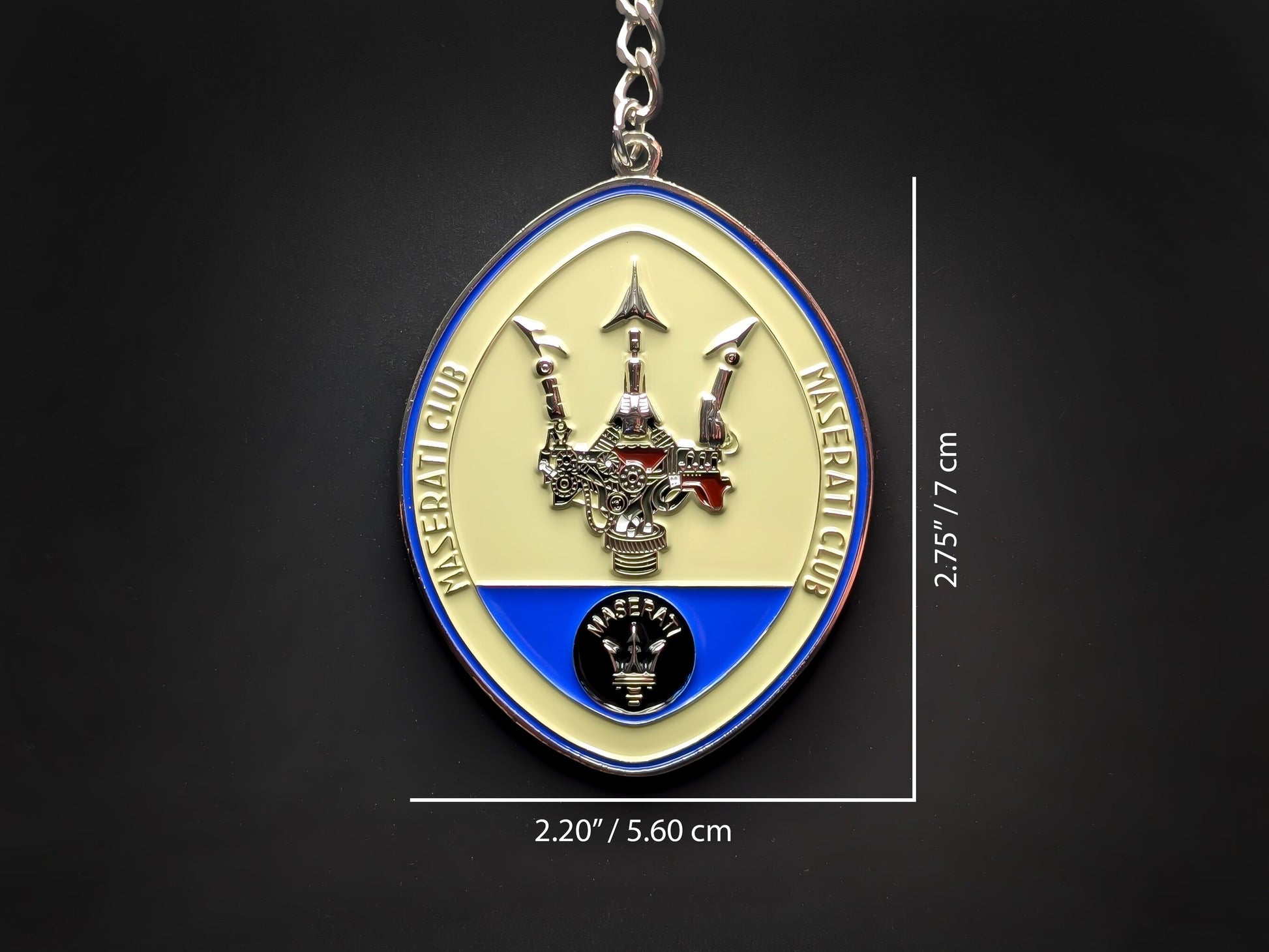 Product dimension shot of the Maserati badge keychain showing it measures 2.75 inches by 2.20 inches (7 cm by 5.60 cm).