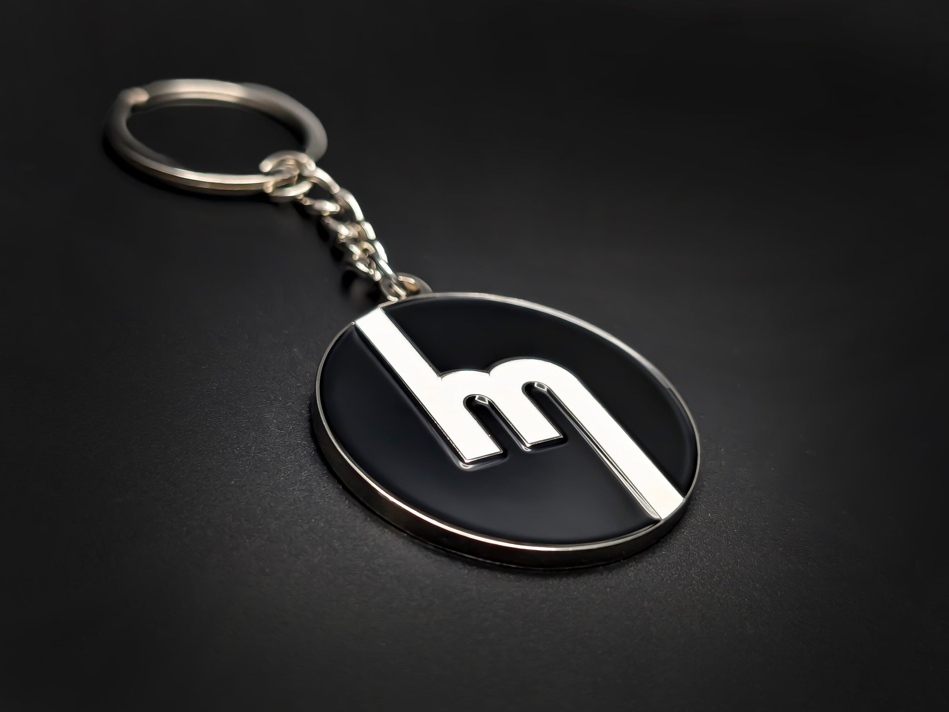 High-quality retro Mazda logo keychain on a dark background, showing the polished silver trim and durable metal chain.