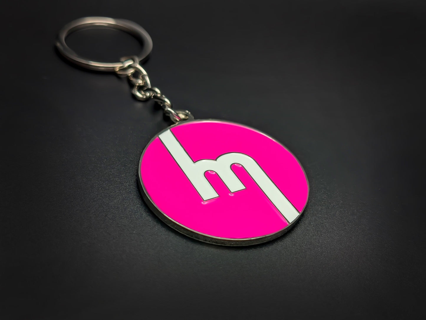 High-quality retro Mazda logo keychain on a dark background, showing the polished silver trim and durable metal chain.