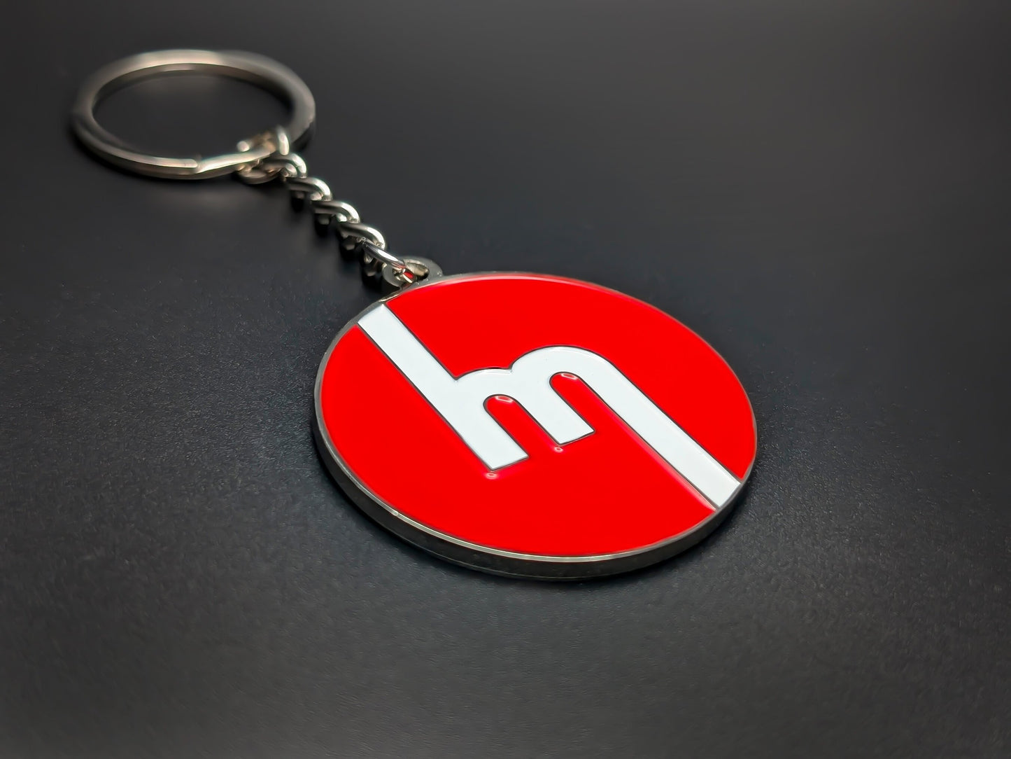 High-quality retro Mazda logo keychain on a dark background, showing the polished silver-tone metal and durable chain.