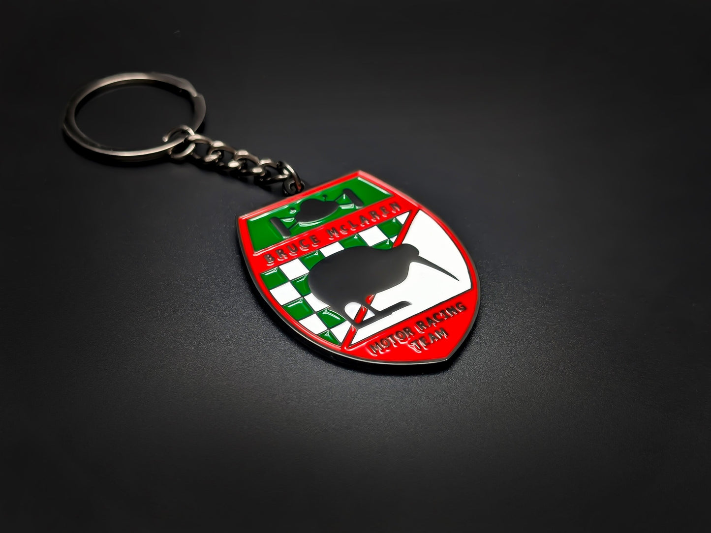 High-quality retro McLaren racing keychain on a dark background, showcasing the vibrant red border and durable gunmetal-finish chain.