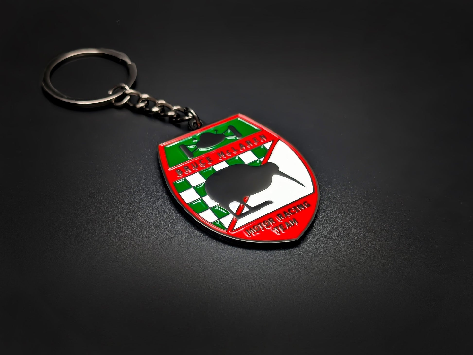 High-quality retro McLaren racing keychain on a dark background, showcasing the vibrant red border and durable gunmetal-finish chain.