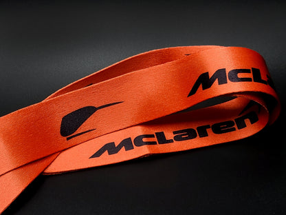 Close-up view of a Papaya Orange satin lanyard highlighting the vintage McLaren Speedy Kiwi racing logo in black.