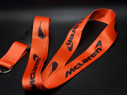 Premium orange McLaren neck lanyard featuring a repeating Speedy Kiwi and modern McLaren wordmark design.
