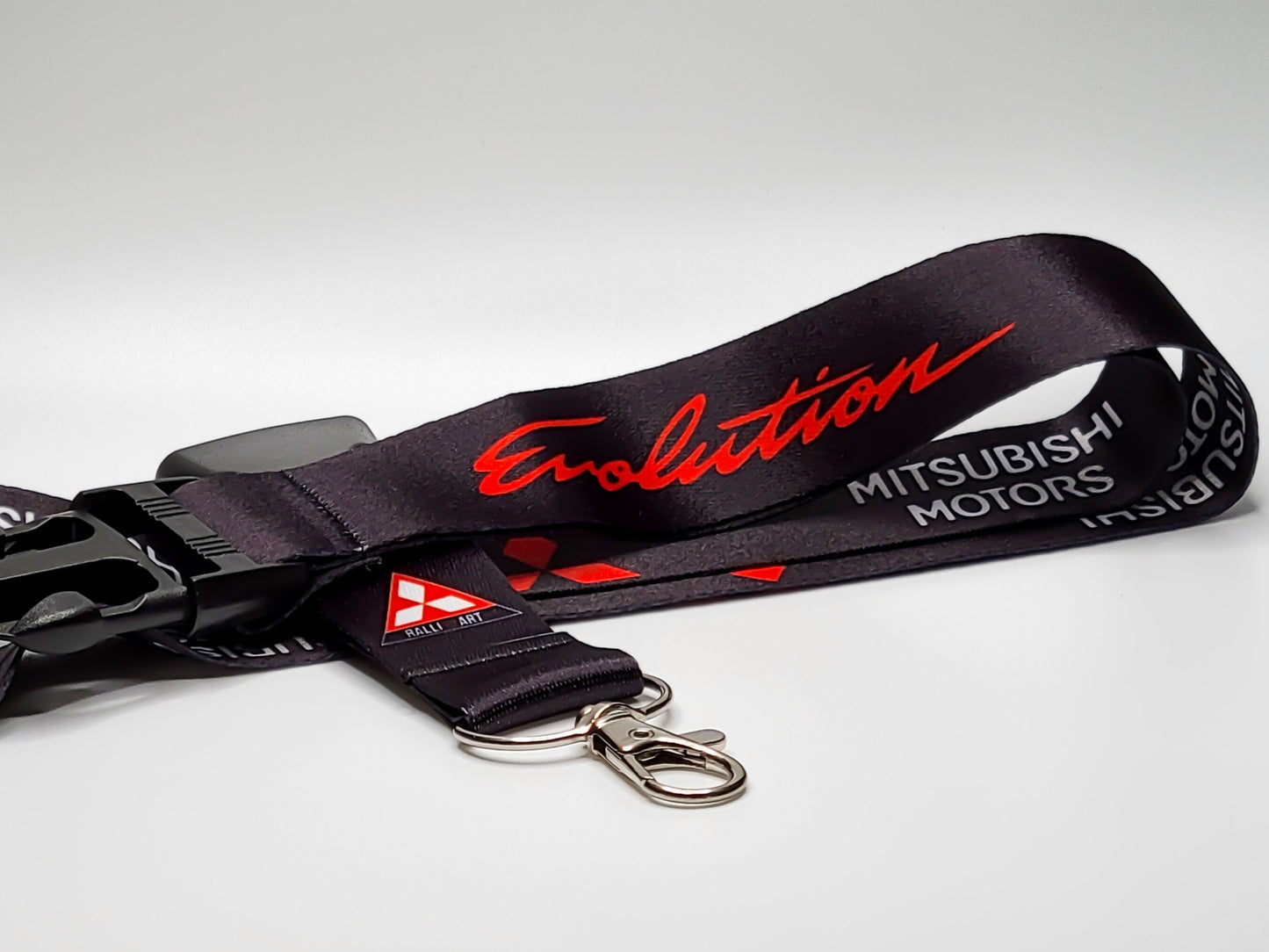 Black Mitsubishi Evolution lanyard featuring red script lettering, white Mitsubishi Motors text, and a Ralliart logo near a silver metal clasp.