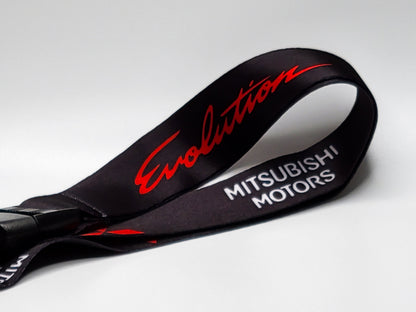 Close-up of a black automotive lanyard highlighting the vibrant red embossed Evolution script and white Mitsubishi Motors block lettering.