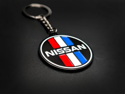 High-gloss Nissan retro competition stripes keychain on a dark background, showing the polished gunmetal chain and metallic rim.