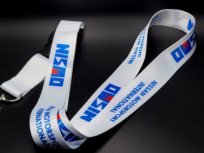Premium white satin lanyard showcasing a repeating blue Nismo logo and "Nissan Motorsport International" wordmark.