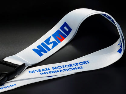 Close-up of a white automotive lanyard highlighting the crisp blue Nismo branding and high-quality fabric texture.