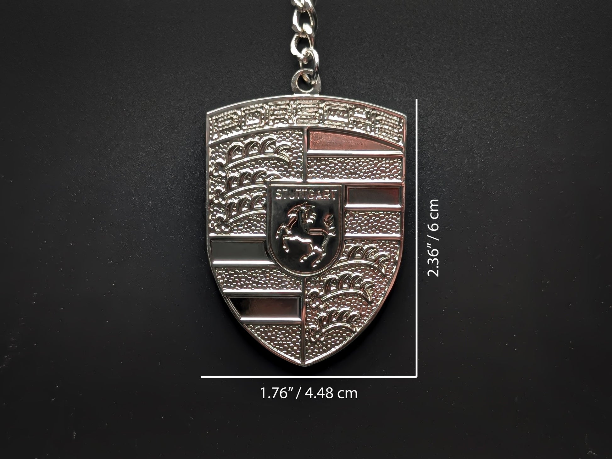 Dimensions of the Porsche silver badge keychain showing a size of 2.36 inches by 1.76 inches (6 cm by 4.48 cm).