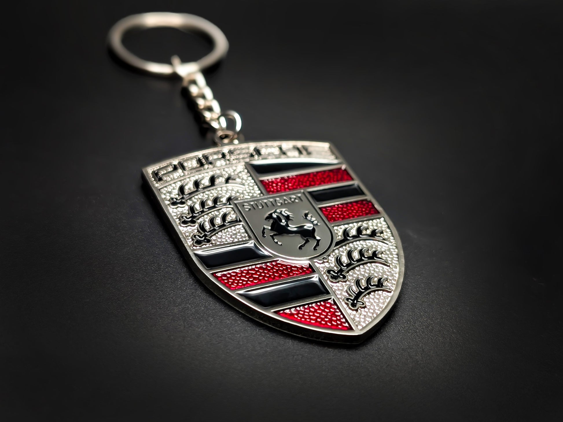 High-quality Porsche red crest keychain on a dark background, showcasing the polished silver trim and durable metal chain.