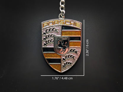 Dimensions of the Porsche yellow badge keychain showing a size of 2.36 inches by 1.76 inches (6 cm by 4.48 cm).