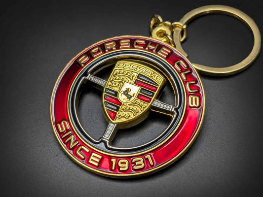 Gold-plated Porsche Club badge keychain on black background, showcasing red enamel border and "SINCE 1931" text.