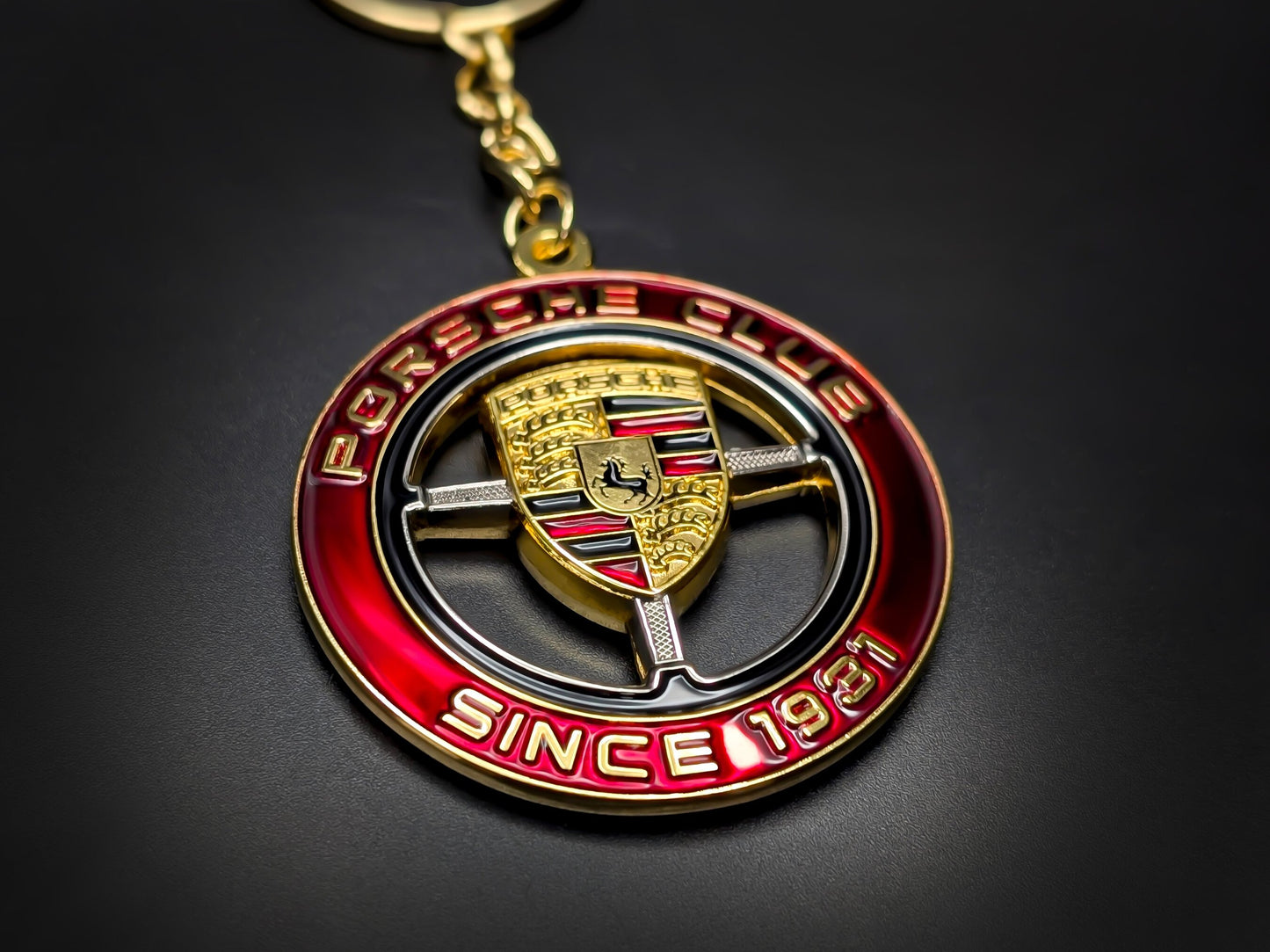 Close-up of heavy-duty metal Porsche Club keychain, highlighting the detailed gold Stuttgart crest and badge construction.