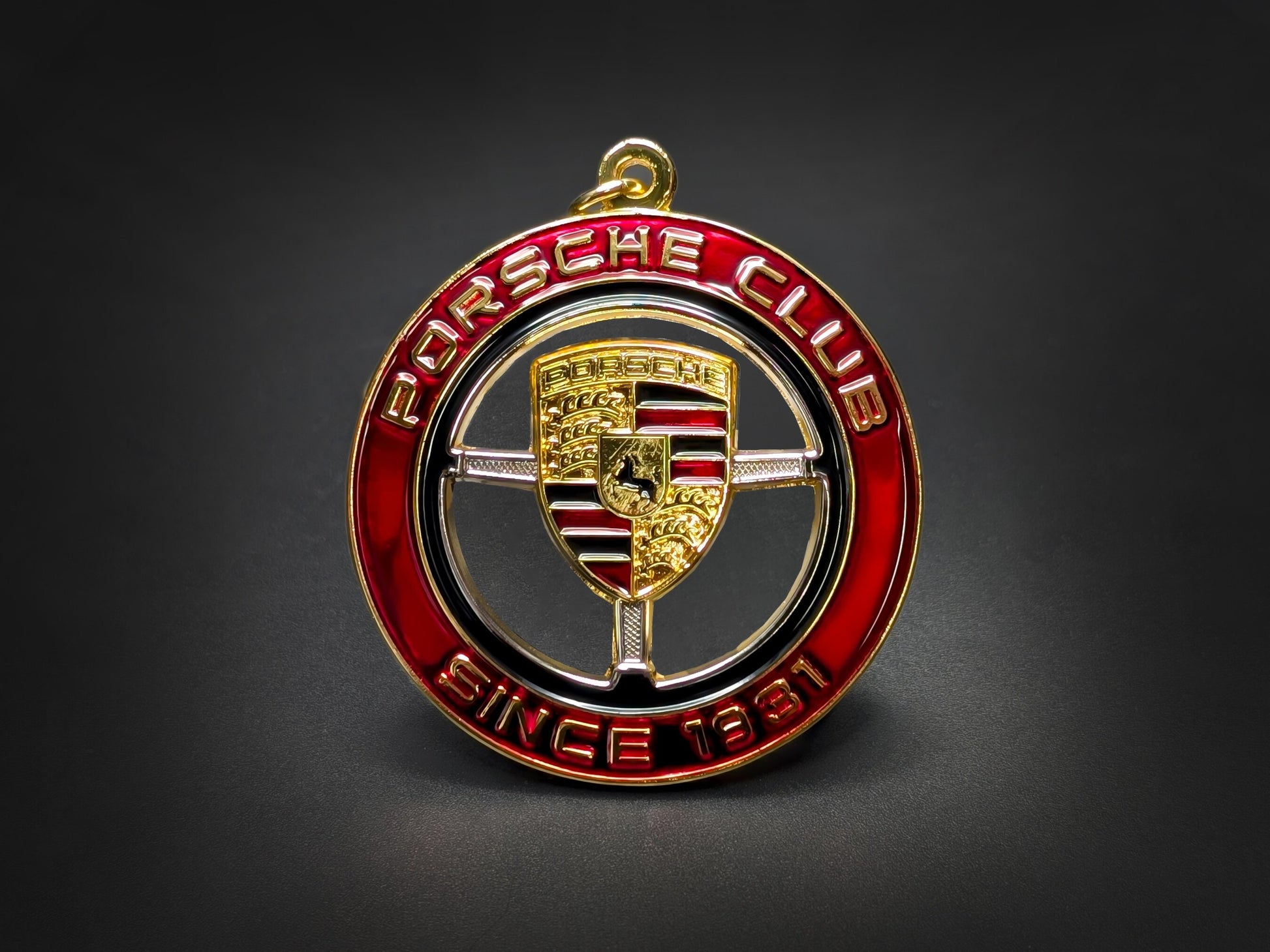 Straight-on studio shot of the premium Porsche Club automotive badge keychain with intricate gold logo and enamel work.