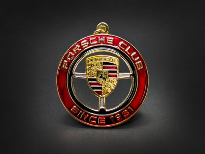 Straight-on studio shot of the premium Porsche Club automotive badge keychain with intricate gold logo and enamel work.
