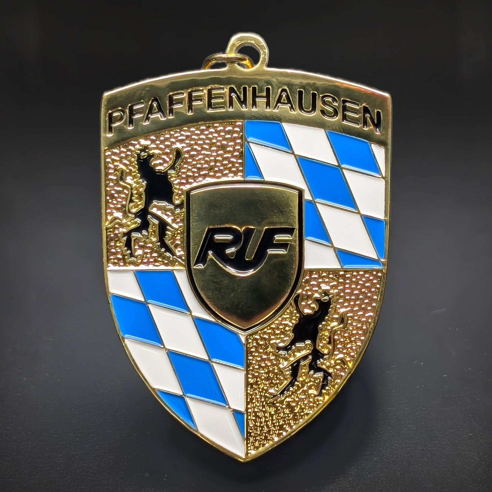 Double-sided metal RUF badge keychain, a gold shield reading ‘PFAFFENHAUSEN’ above a blue-and-white diamond pattern, gold rampant lions, and a black ‘RUF’ crest, on a jump ring on a dark background.