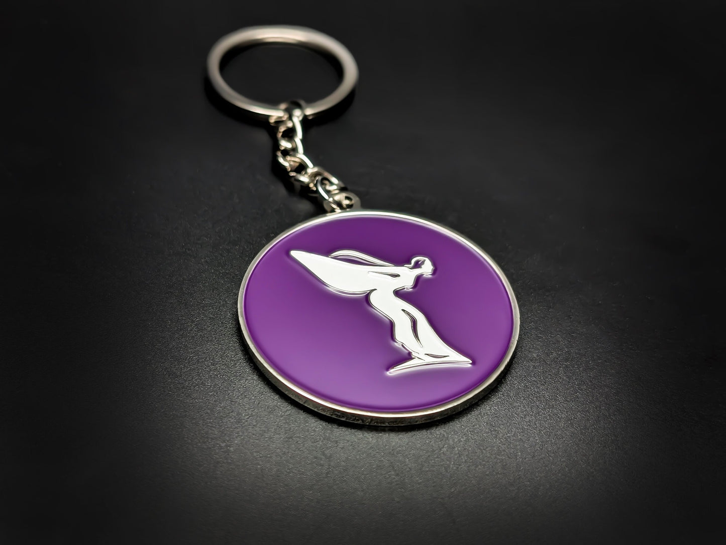 High-gloss purple Rolls-Royce Spirit of Ecstasy badge keychain on a dark surface, showing the polished silver chain and ring.