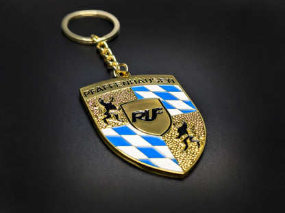 High-quality RUF Porsche badge keychain on a dark background, showcasing the polished gold finish and heavy-duty metal chain.