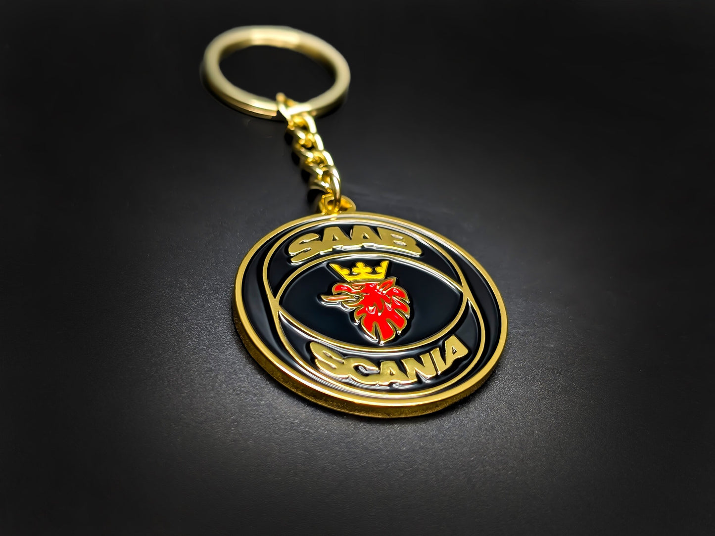 High-quality Saab Scania heritage keychain in black and gold on a dark background, showcasing the polished gold-tone link chain.