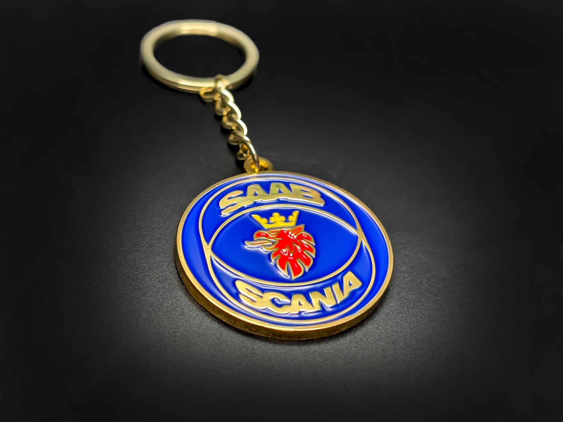 High-quality Saab Scania heritage keychain on a dark surface, showcasing the polished gold-tone linked chain and glossy enamel.