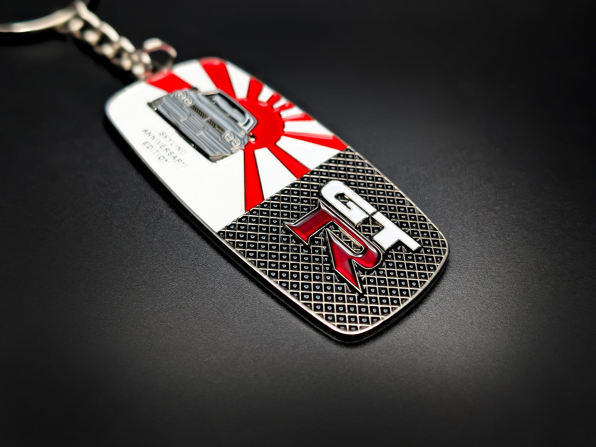 High-quality JDM Skyline GT-R metal badge keychain showing the textured black mesh background and red enamel GT-R lettering.