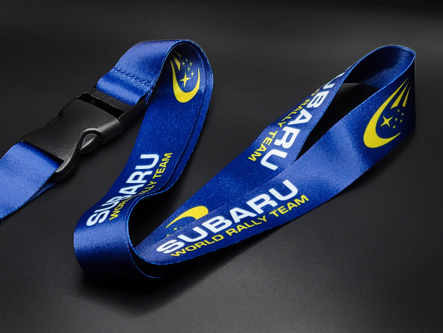 Subaru Rally JDM neck lanyard with a repeating pattern of the World Rally Team logo and yellow stars on a vibrant blue background.