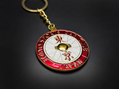 High-quality JDM style Tokyo car club badge keychain on a black background, showing the gold plating and chain.