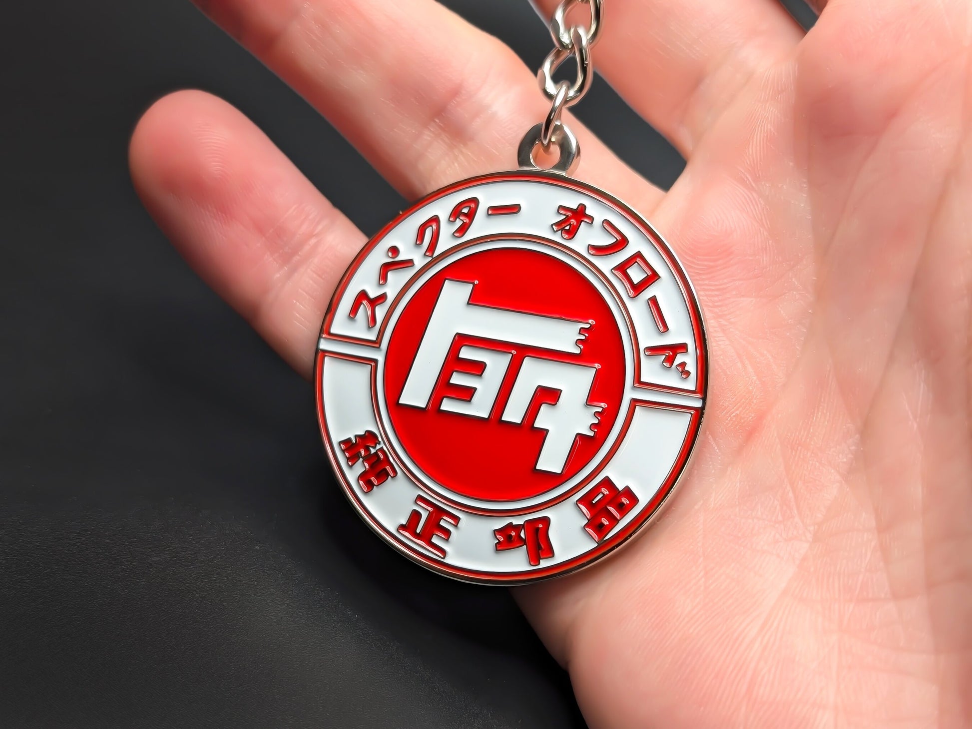 Hand holding a circular Toyota JDM enamel badge keychain to demonstrate the premium metallic weight and vibrant 3D finish.