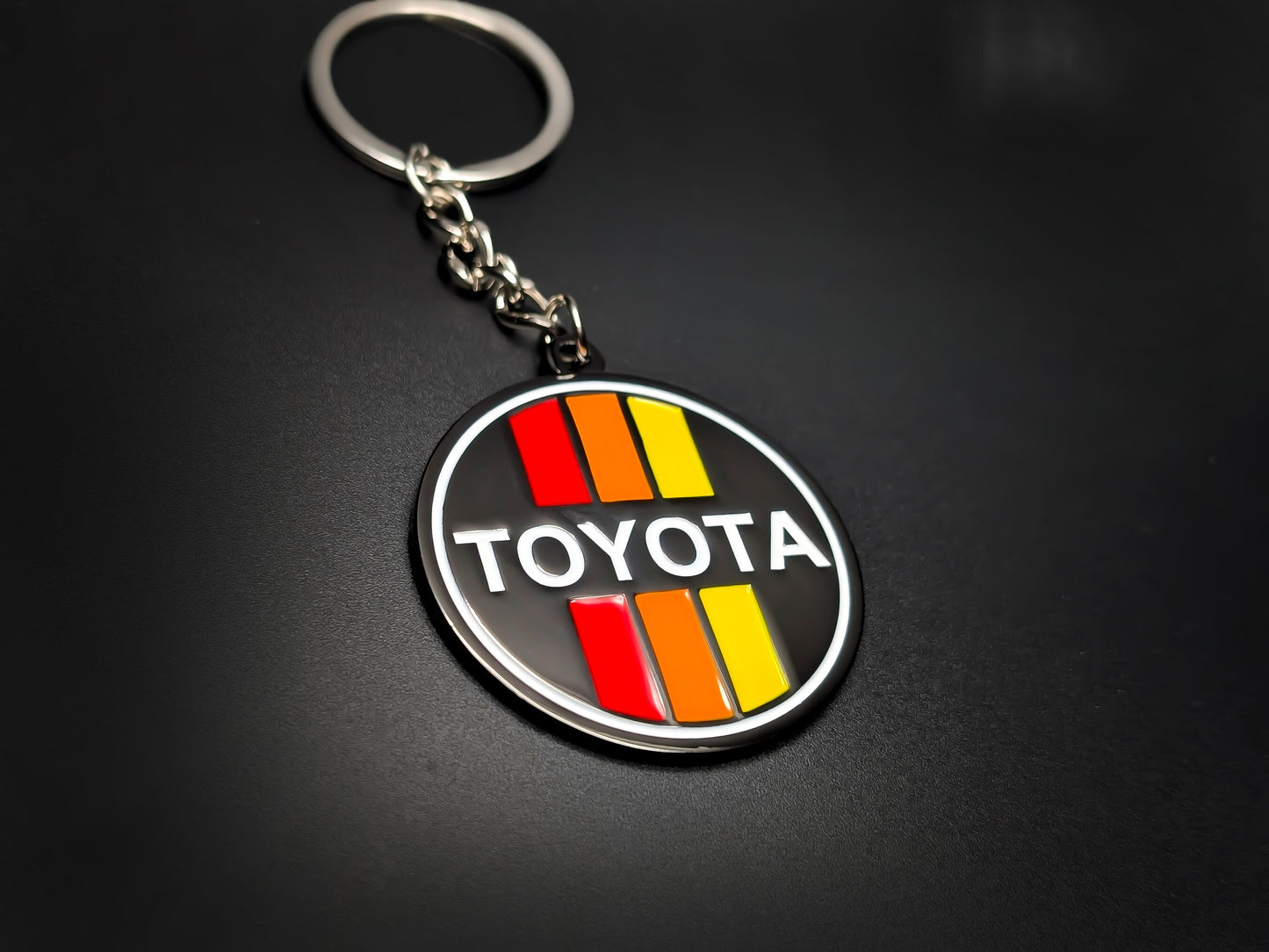 High-quality Toyota retro tricolor racing keychain on a dark background, showcasing the polished silver-tone rim and linked chain.