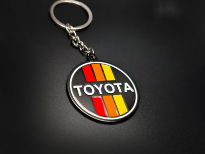 High-quality Toyota retro tricolor racing keychain on a dark background, showcasing the polished silver-tone rim and linked chain.