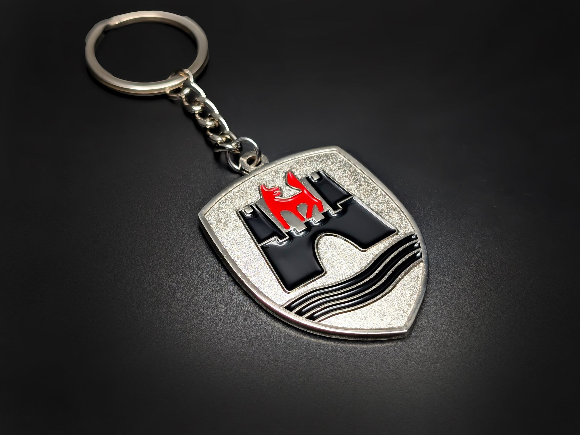 High-quality VW Wolfsburg shield keychain on a dark background, showing the polished metal chain and enamel details.