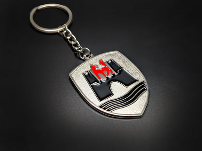 High-quality VW Wolfsburg shield keychain on a dark background, showing the polished metal chain and enamel details.